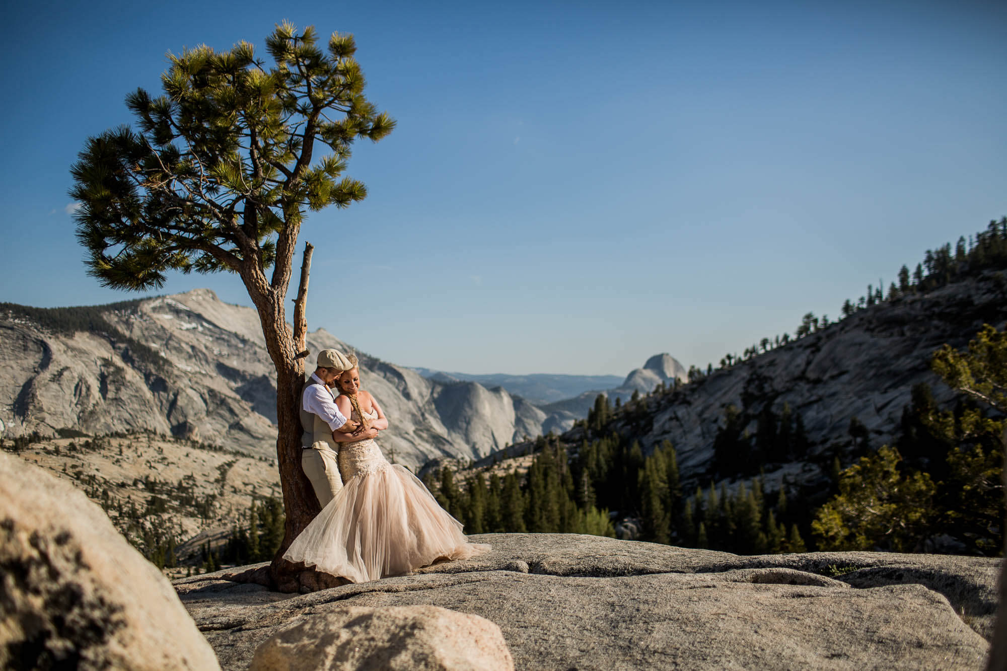Bride and groom snuggling against a tree at Olmstead Point in Yosemite National Park