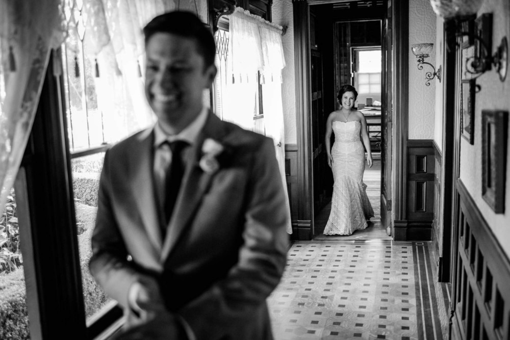 Bride smiles as she walks toward her smiling groom during their first look at The Winchester Mystery House in San Jose, CA