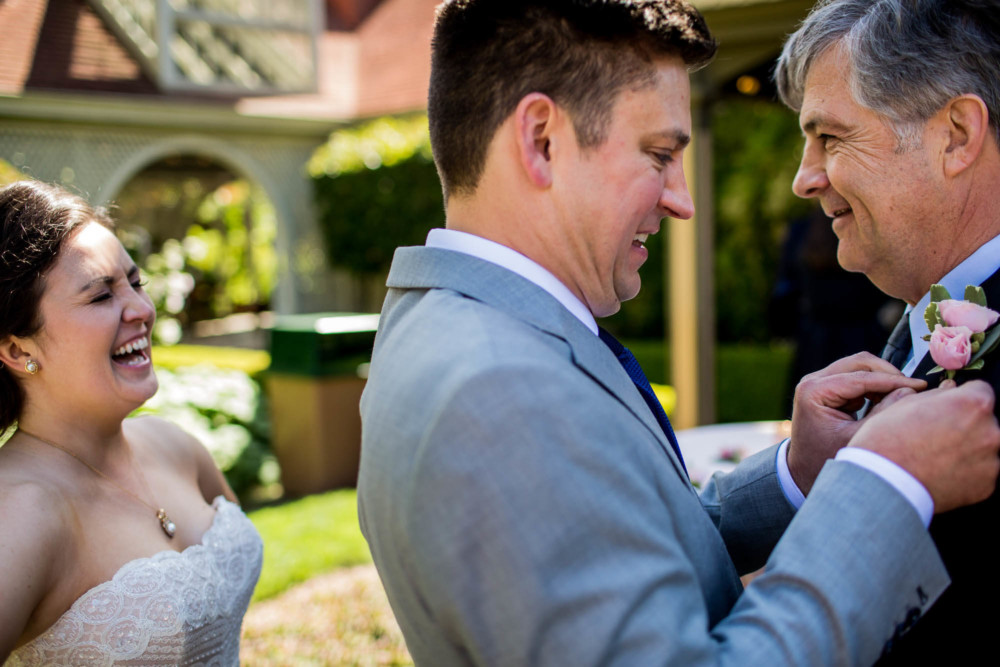 Groom pins a boutonniere on the brides father at The Winchester Mystery House in San Jose, CA