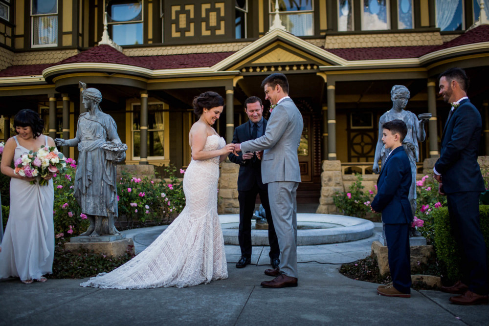 Bride places the ring on the groom's finger during their wedding ceremony at the Winchester Mystery House in San Jose, CA