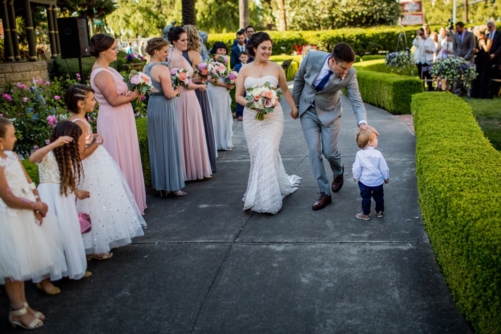 Groom pats a toddler on the head as they walk down the aisle after their wedding at the Winchester Mystery House in San Jose, CA