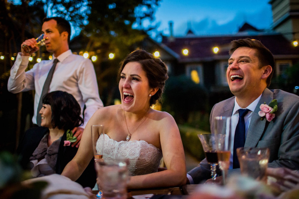 A bride and groom react with laughter to a toast during their wedding reception at the Winchester Mystery House