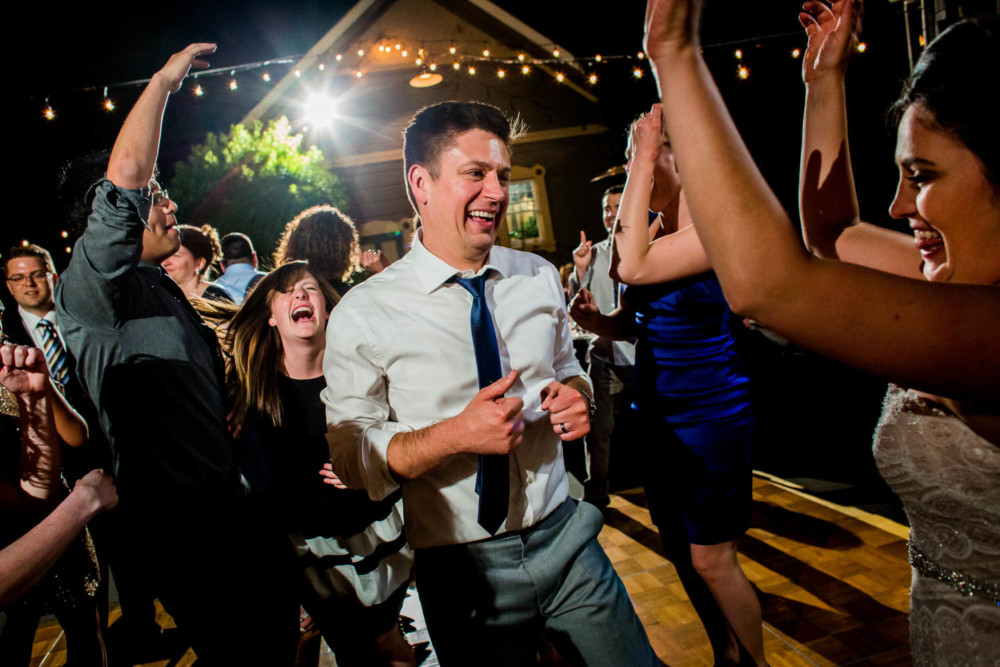 The bride and groom with group of wedding guests dancing at a reception at the Winchester Mystery House in San Jose, CA