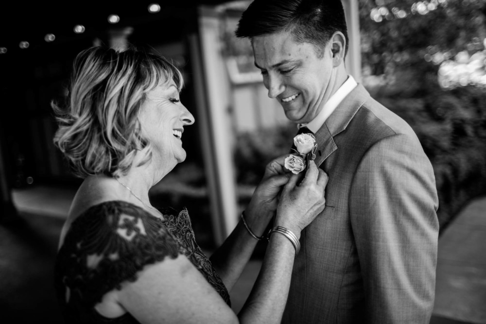 Mother of the groom pins the boutonniere before the wedding at The Winchester Mystery House in San Jose, CA