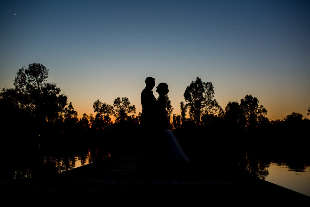 Silhouette of the bride and groom by the lake at Wolf Lakes Park in Sanger, CA