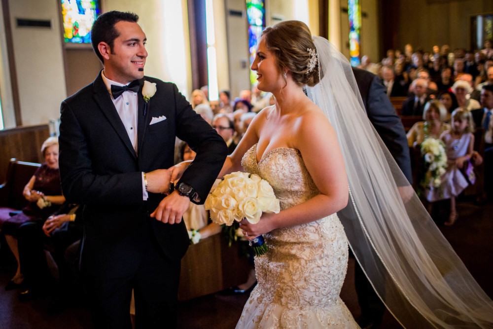 Groom meets the bride at the head of the aisle before their wedding ceremony at Pilgrim Armenian Church in Fresno, CA