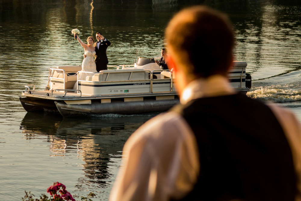 Bride and groom arrive to their wedding reception riding a pontoon boat at Wolf Lakes Park