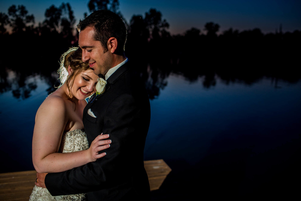 Portrait of a bride and groom at dusk by a lake at Wolf Lakes Park in Fresno, CA