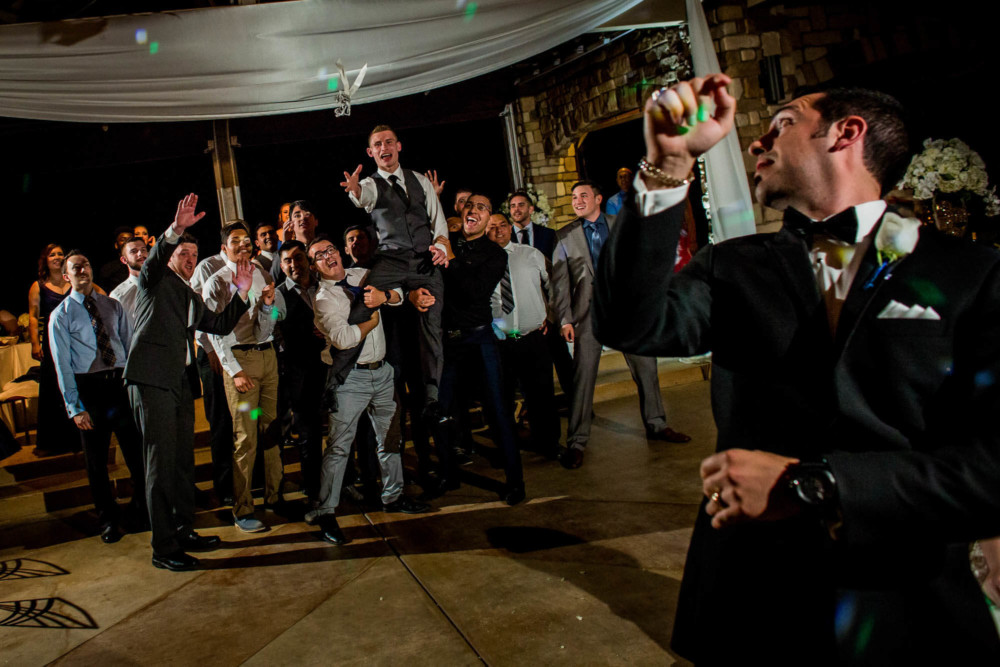 Groom tossing the garter at a wedding reception at Wolf Lakes Park in Fresno, CA