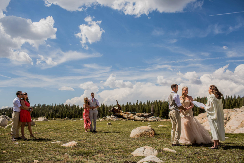 Guests watch as a Bride and Groom elope under a dramatic sky in Tuolumne Meadows in Yosemite National Park
