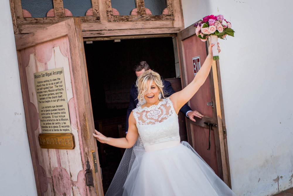 Bride throws her arm in the air while exiting the church after the wedding