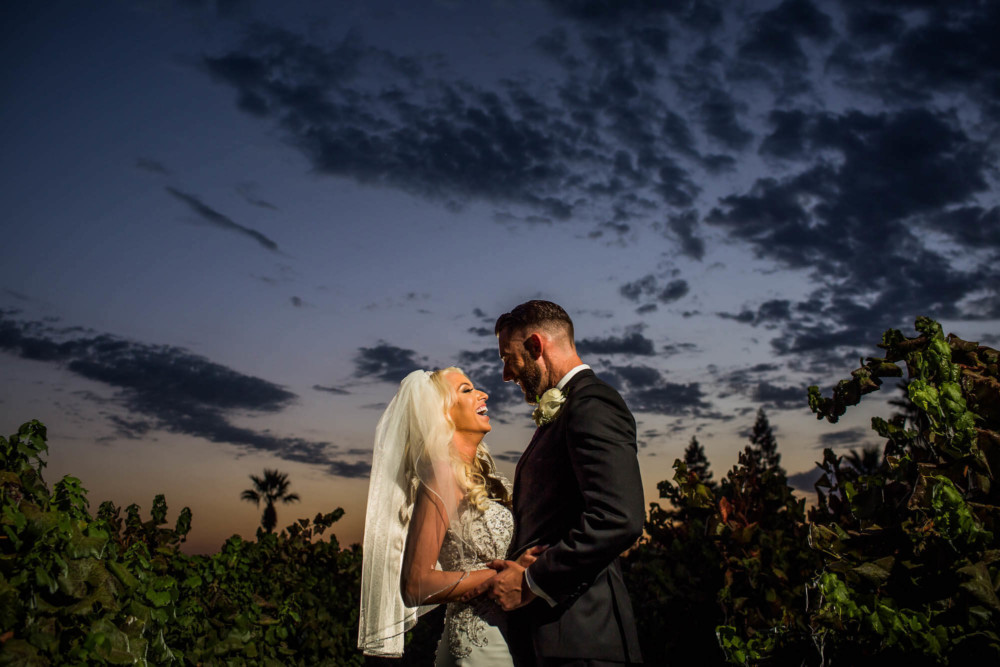 A bride and groom laughing in a vineyard at sunset at Copper River Country Club