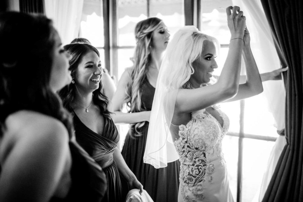 Bridesmaids help the bride put on her veil before her wedding at Copper River country Club