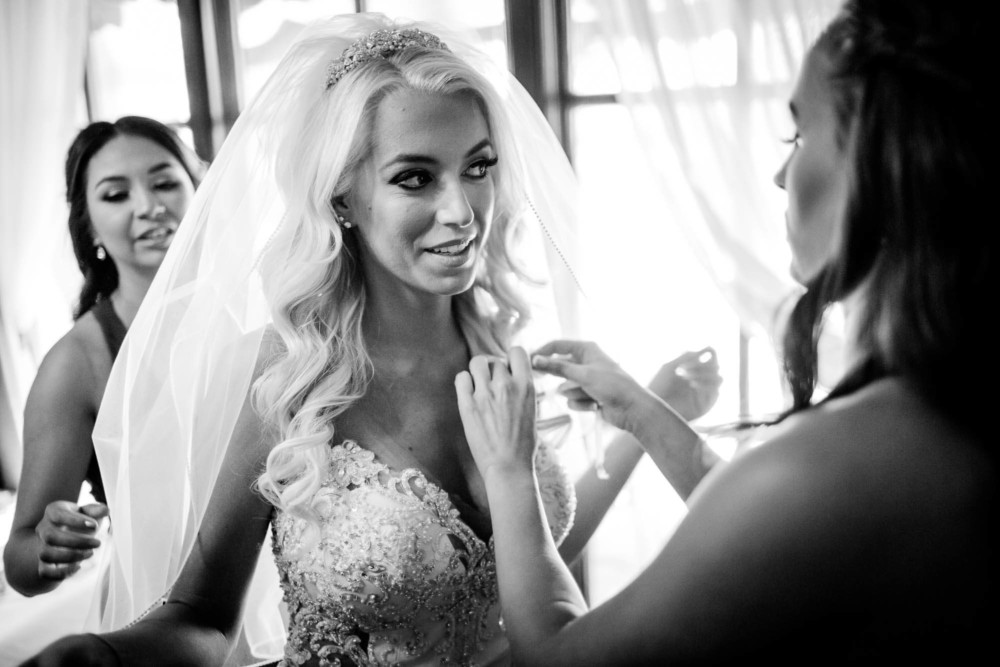 A bride looks at herself in a mirror before her wedding at Copper River Country Club