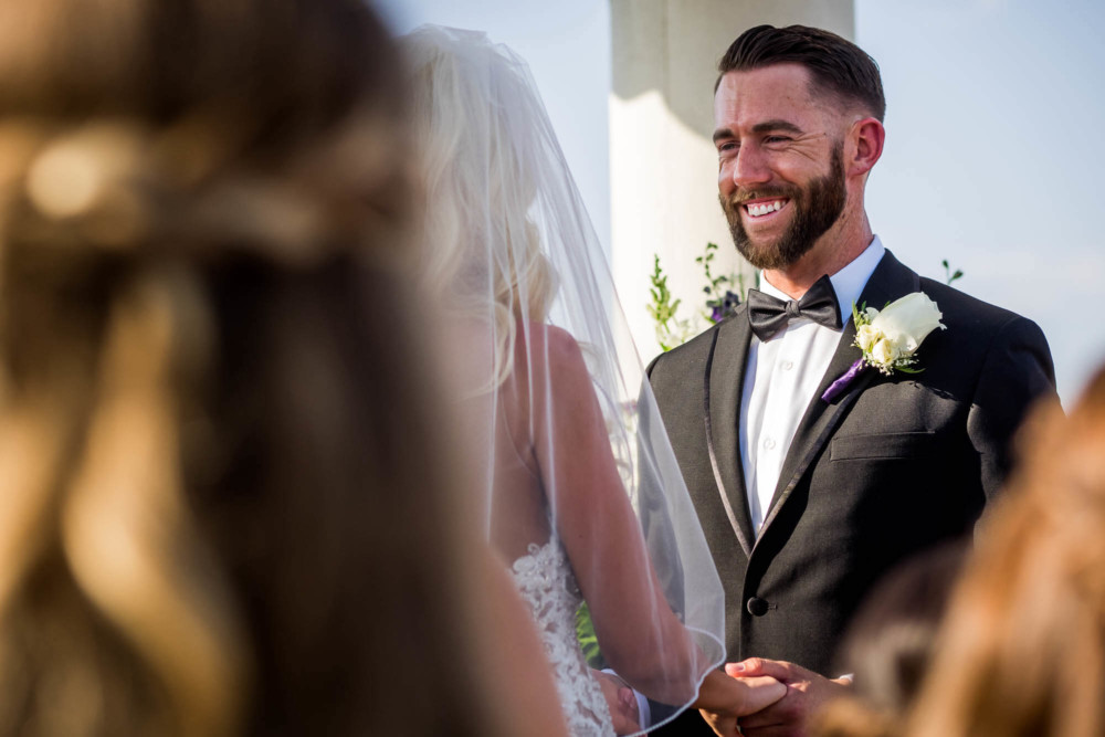 Groom laughs during their wedding ceremony at Copper River Country Club