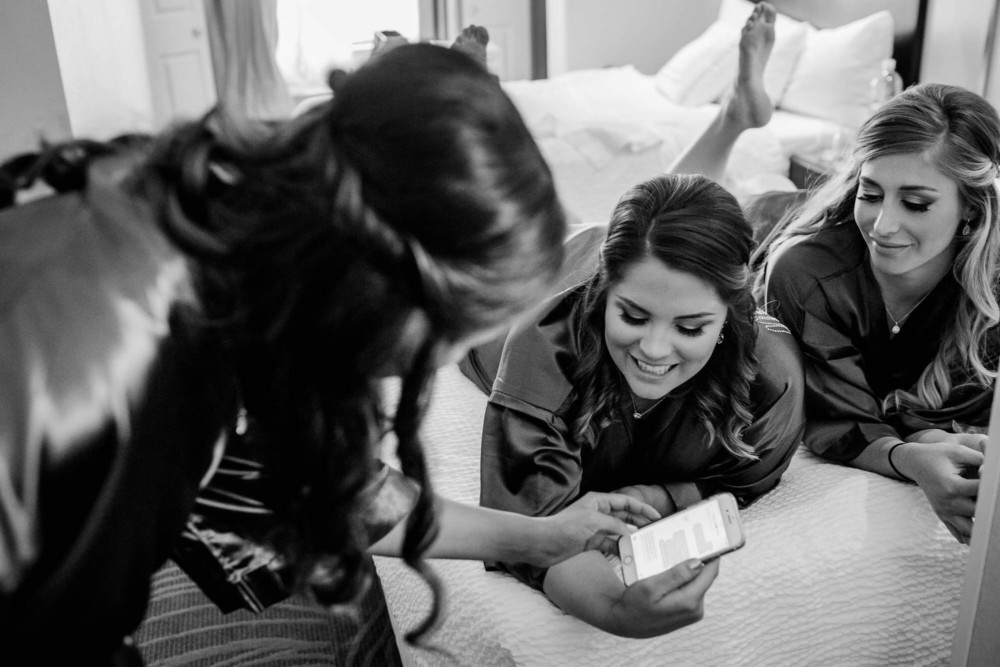 Bridesmaids laughing over something on a phone screen