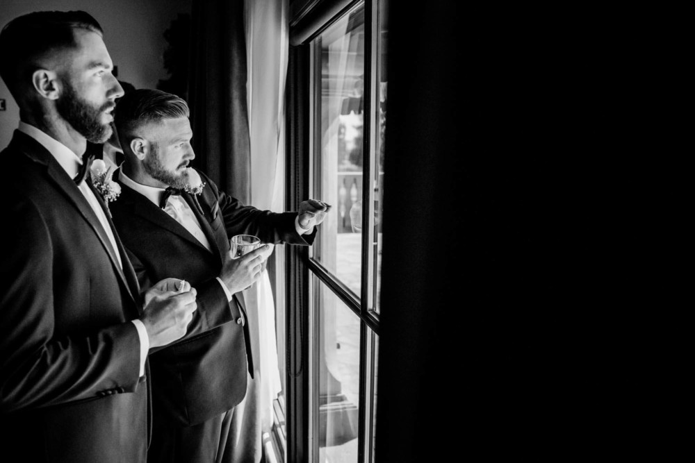 Groom and groomsmen look out the window over the golf course at Copper River Country Club