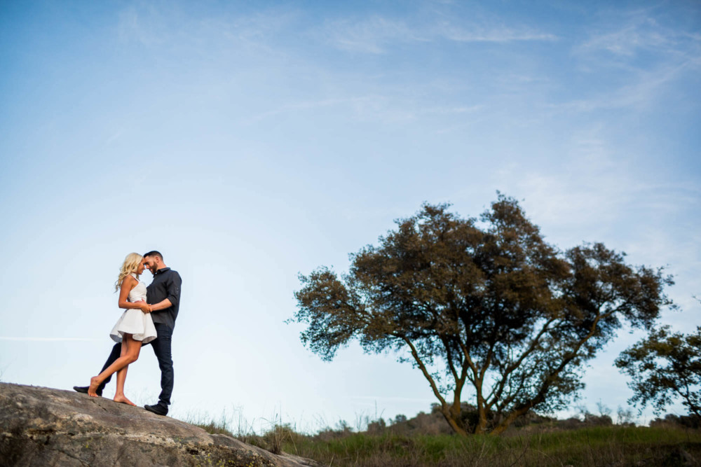 Engaged couple embracing on a granite rock during their engagement session