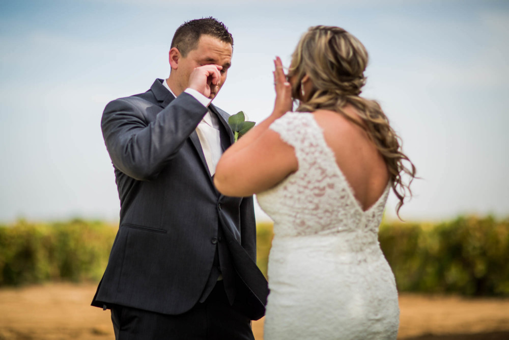 Bride and groom wipe away tears during their first look at Moravia Wines