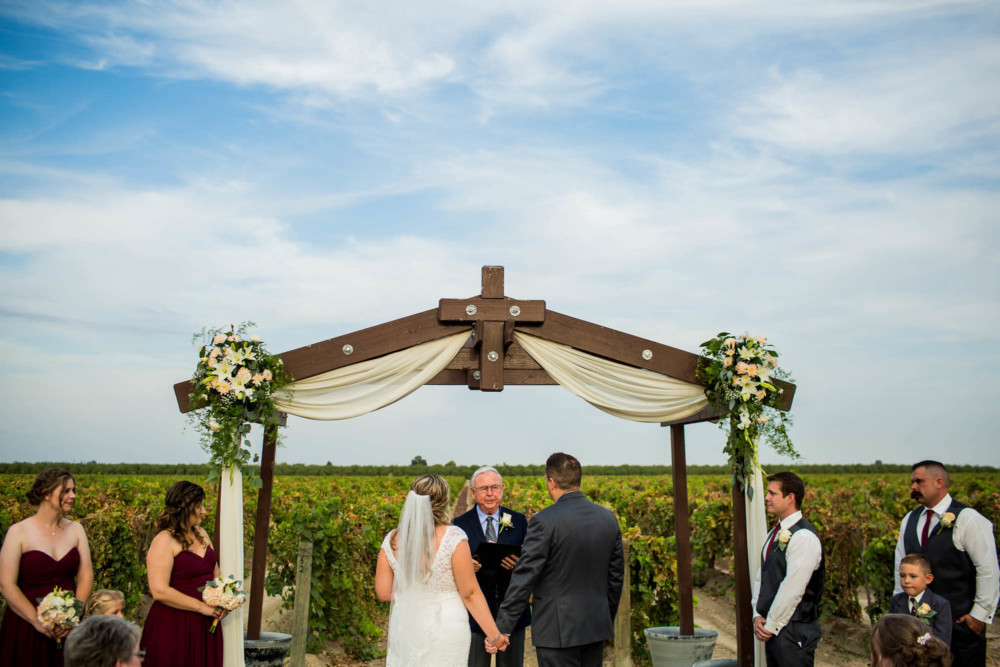 Bride and groom during their ceremony overlooking a vineyard