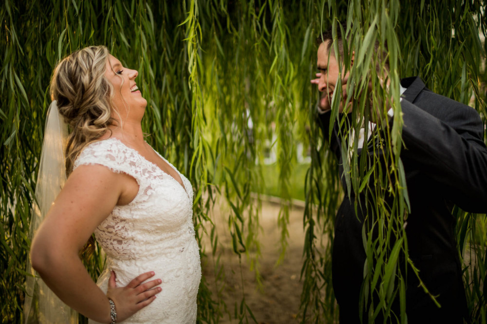 Bride and groom being silly in a willow tree