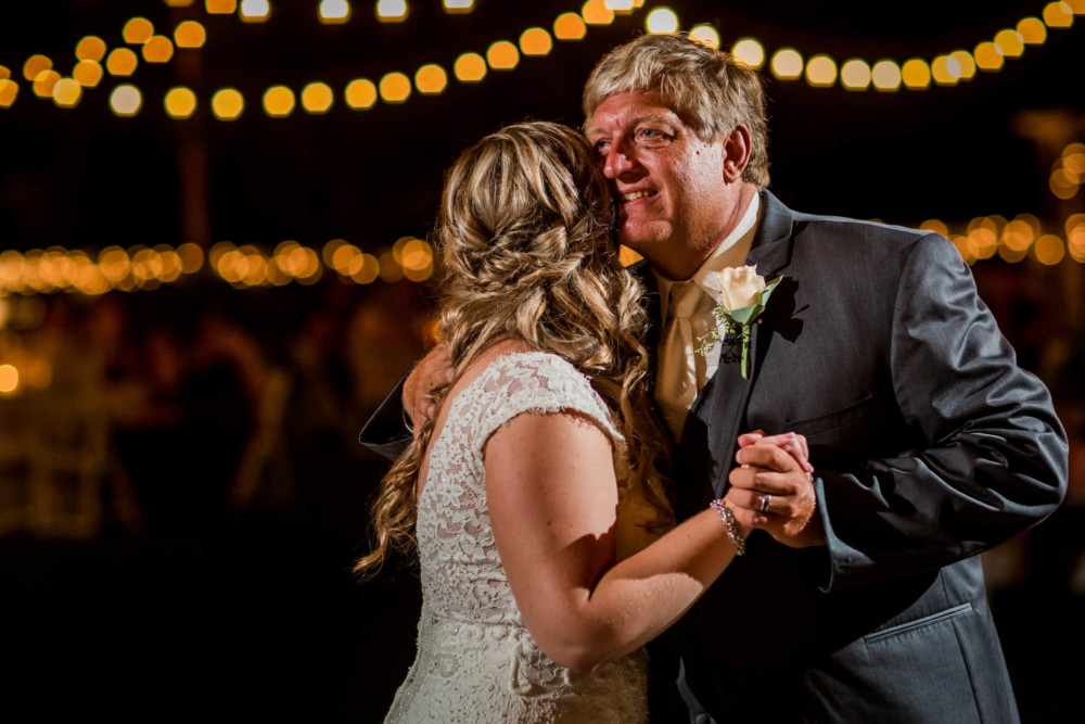 Father of the bride smiles and hugs his daughter during the father-daughter dance
