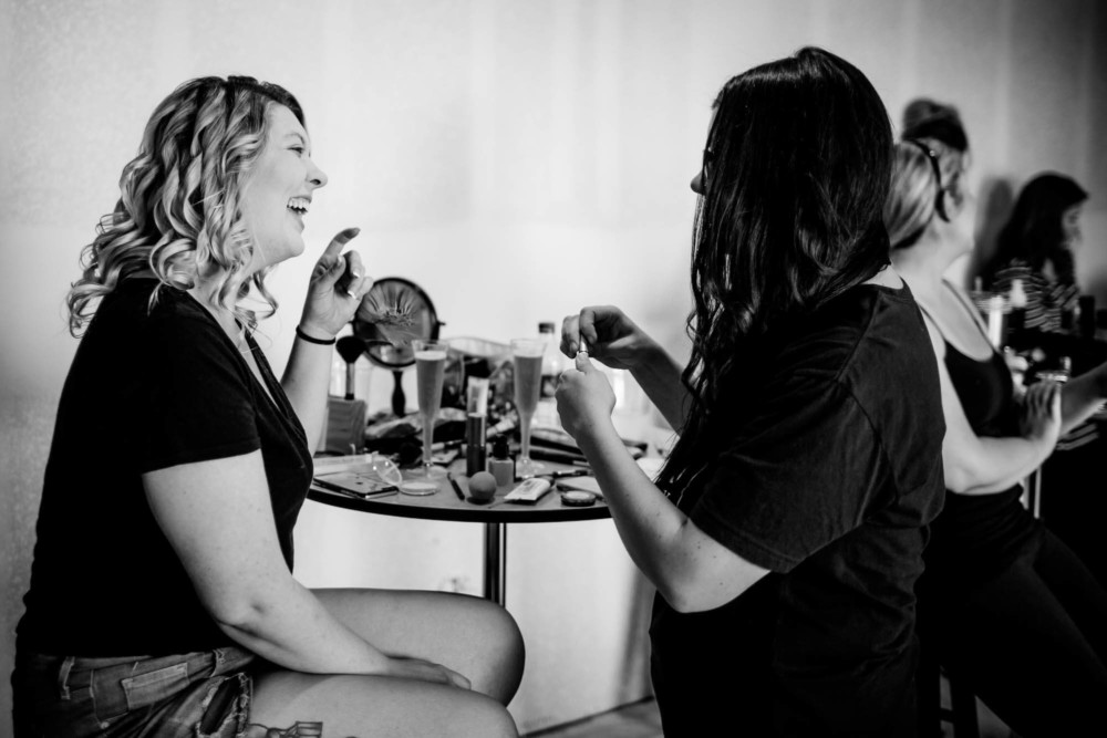 Bridesmaid laughing while having her makeup done