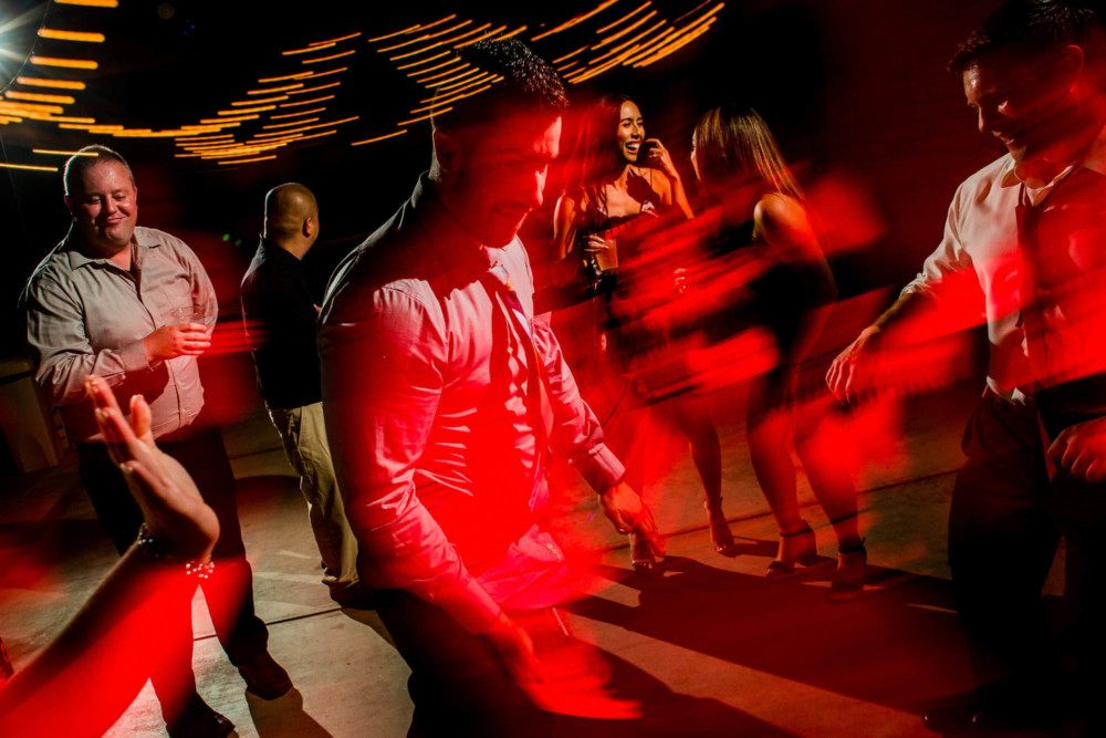 Guests dance under colorful lights during the wedding reception