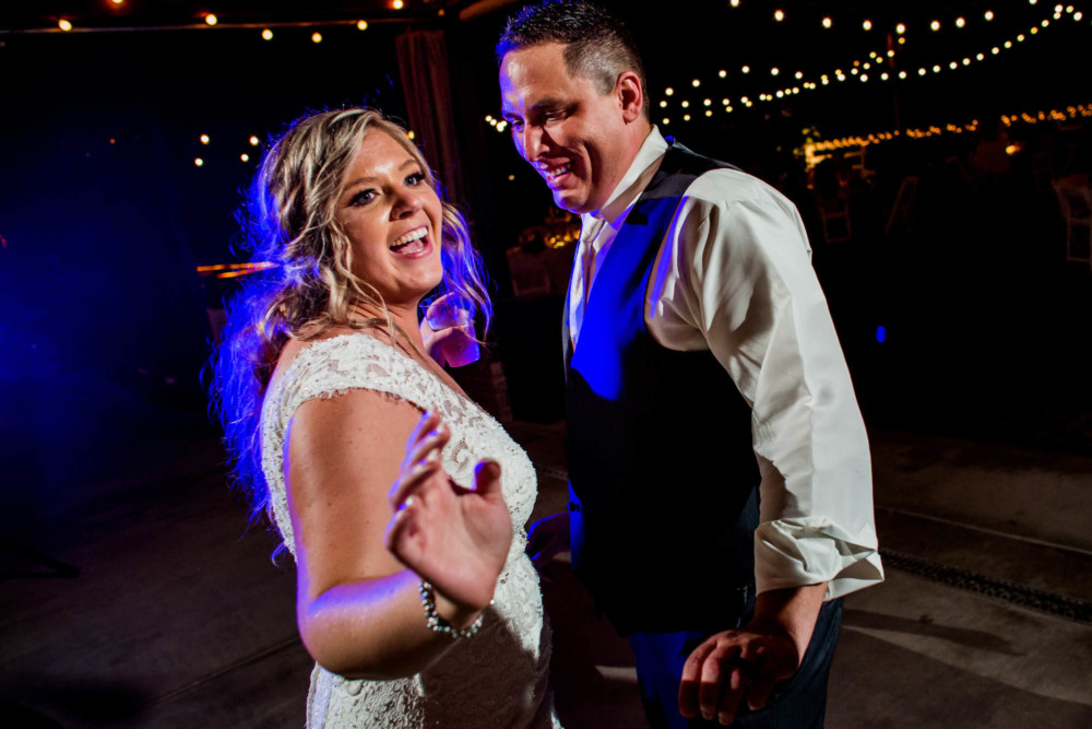 Bride and groom dance under colorful lights during their wedding reception