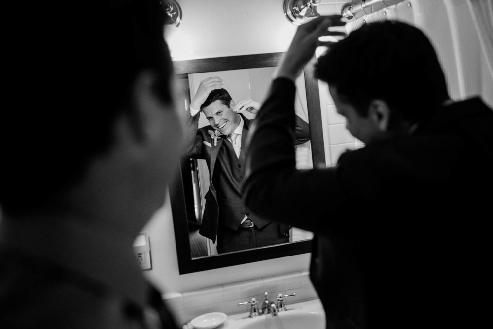 Groom does his hair reflected in mirror