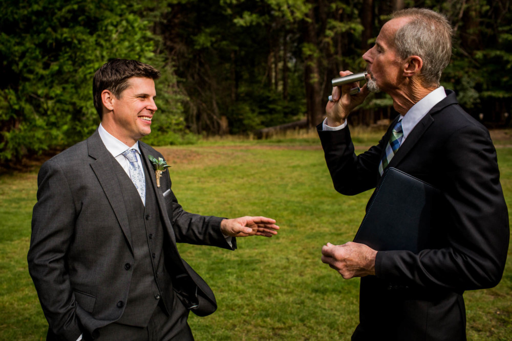 The groom and the officiant sharing a flask of whiskey before the ceremony