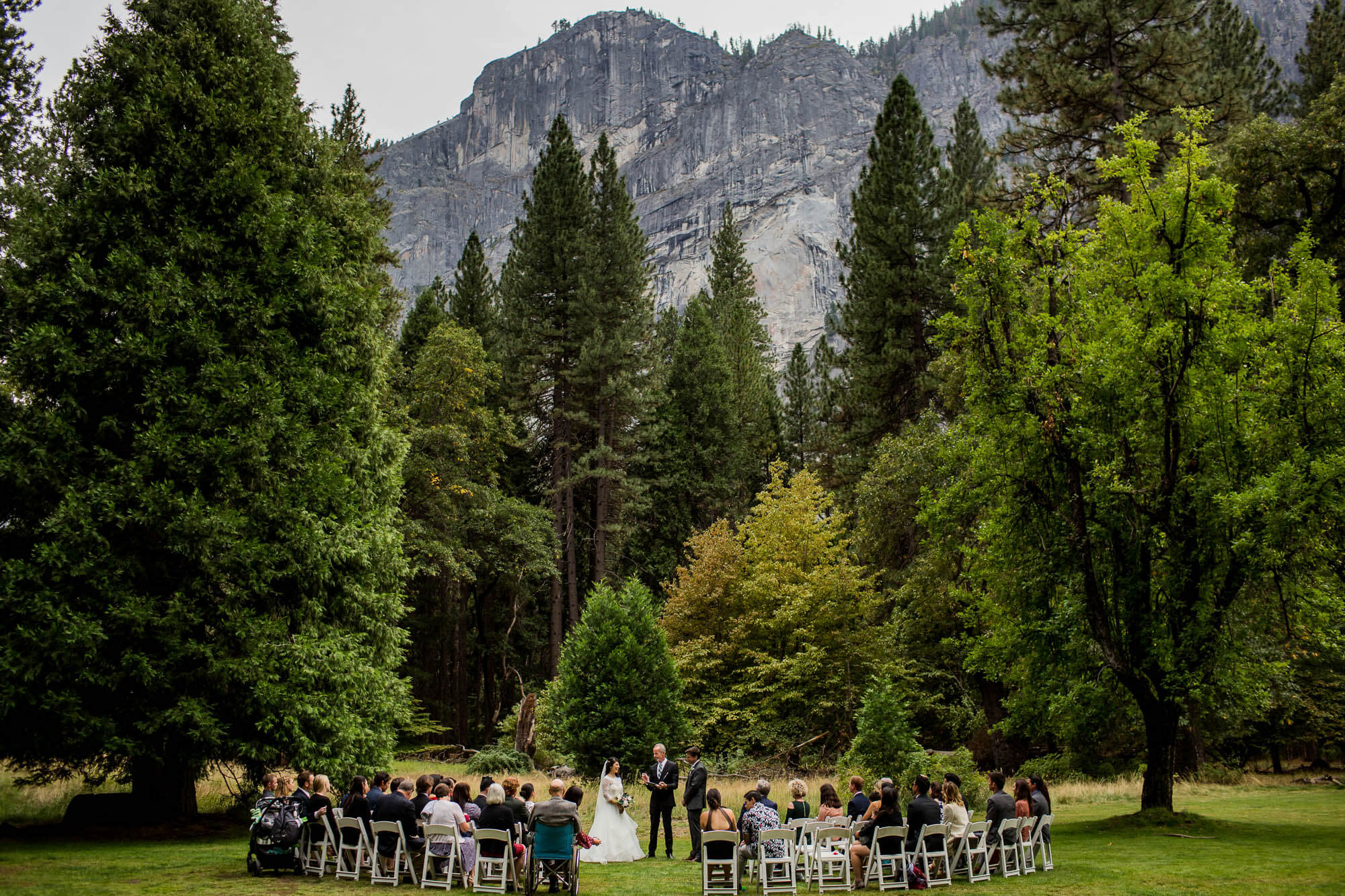 Wide shot of a wedding ceremony with Glacier Point in the background