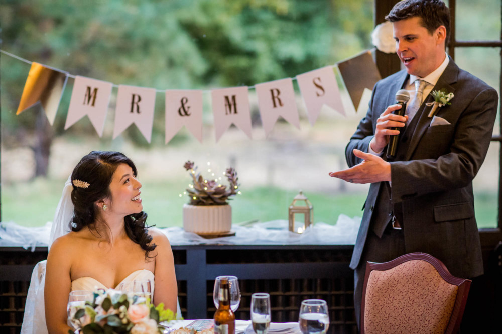 Bride and groom laugh during speeches at their reception