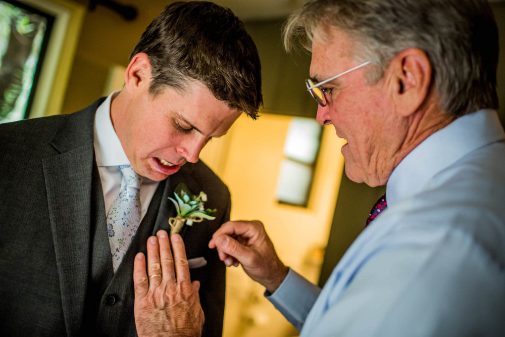 Father of the groom pins the boutonniere on his son