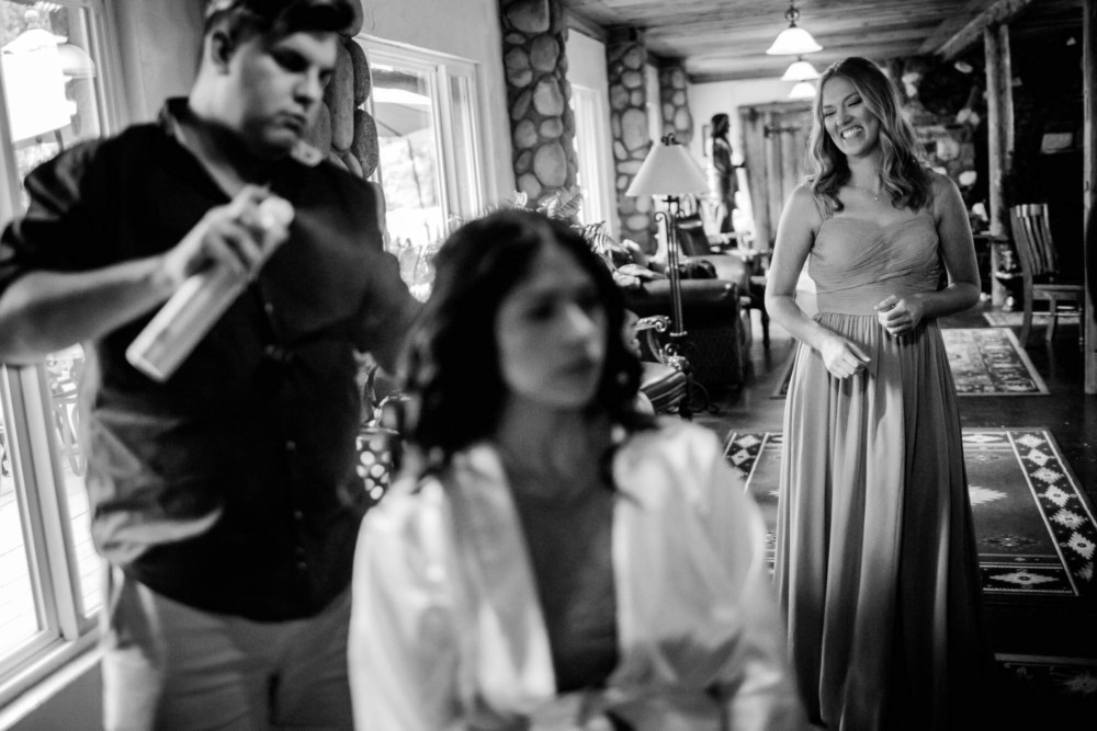 Bridesmaid looks on and laughs as the bride gets her done