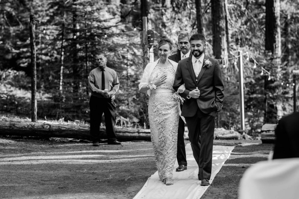 Groom walks his mother down the aisle during the wedding ceremony