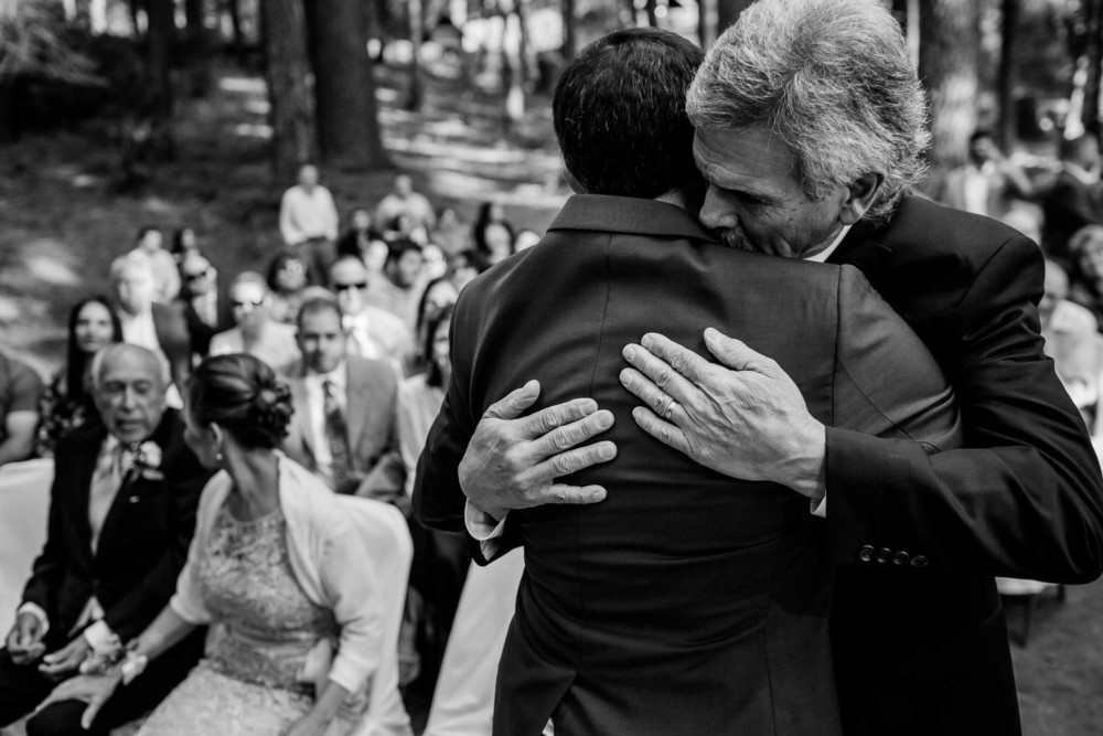 Groom hugs his father before she sits during the wedding ceremony