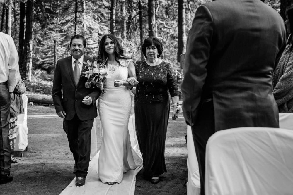 Bride escorted down the aisle by her parents during her wedding ceremony