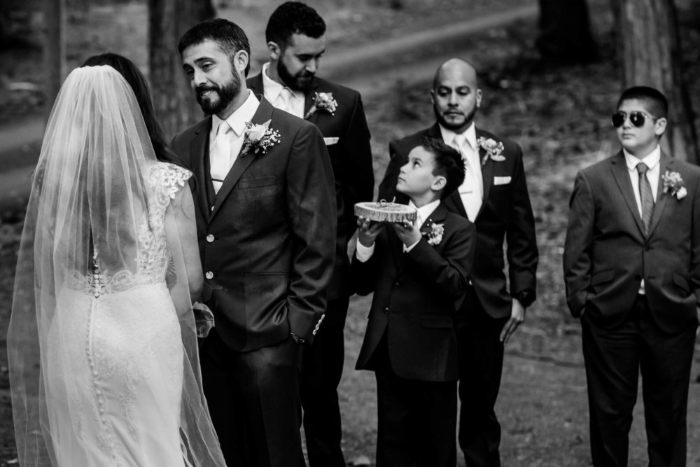 Groom looks at his wife with the ring bearer in the background
