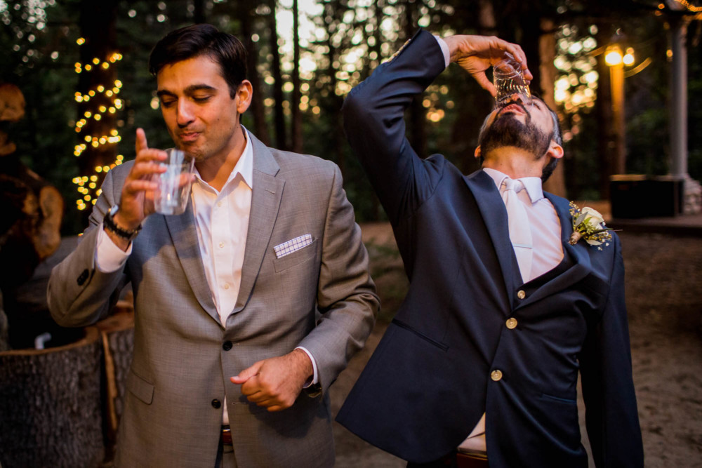 Groom takes a shot with his friend at the wedding reception