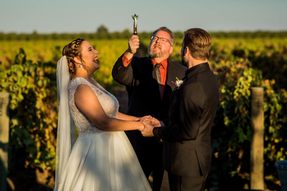 Bride and groom laugh at officiant's surprise during the wedding