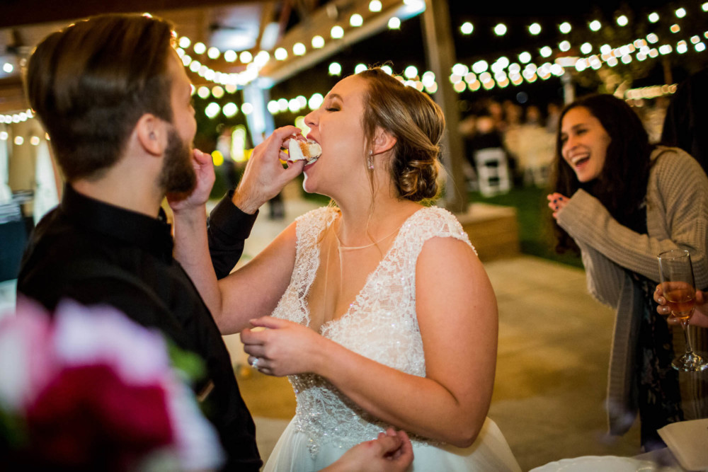 Bride and groom stuffing cake into each others faces