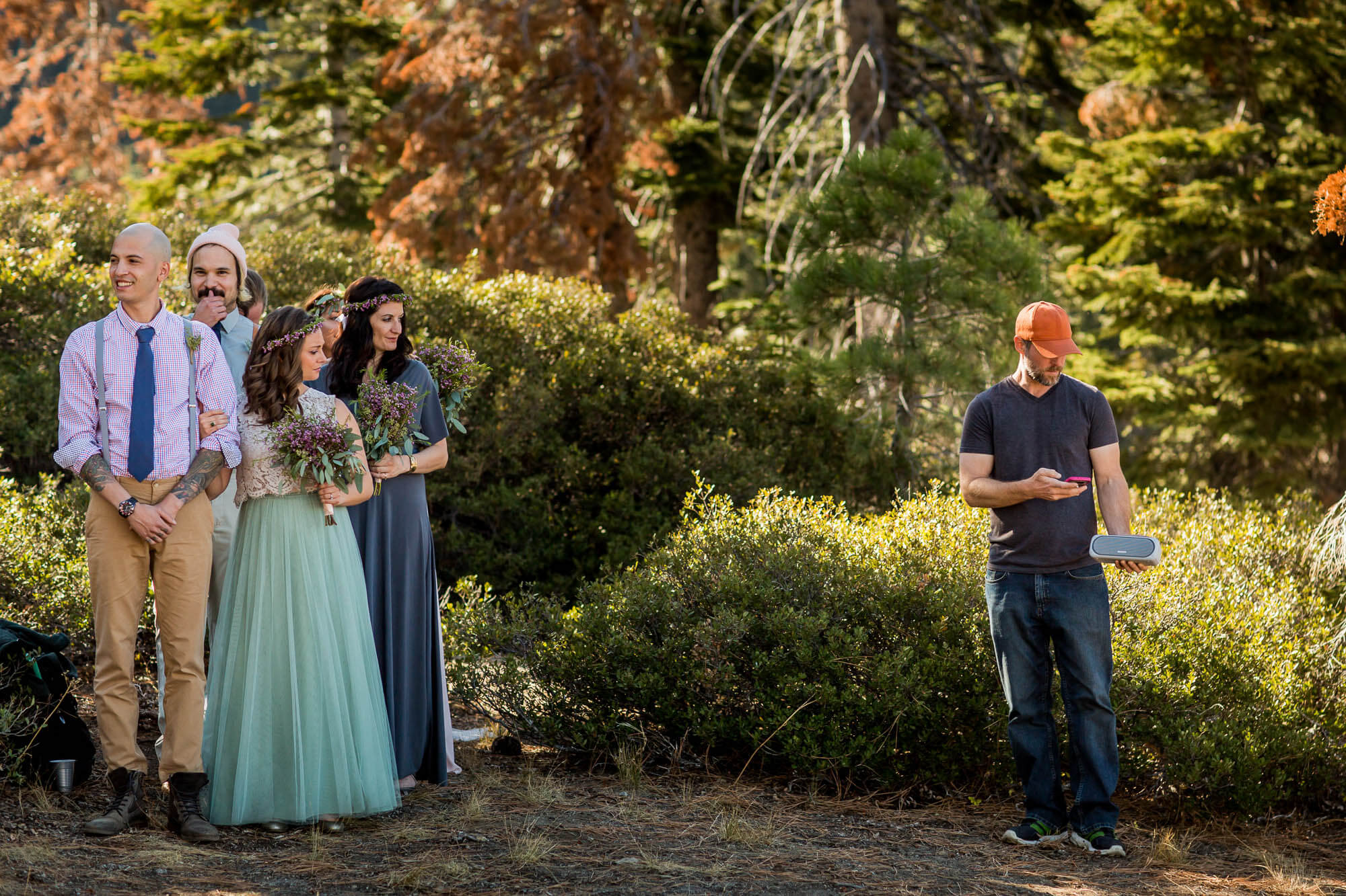 Bridal party waits for the processional while a man in an orange hat tries to start the music