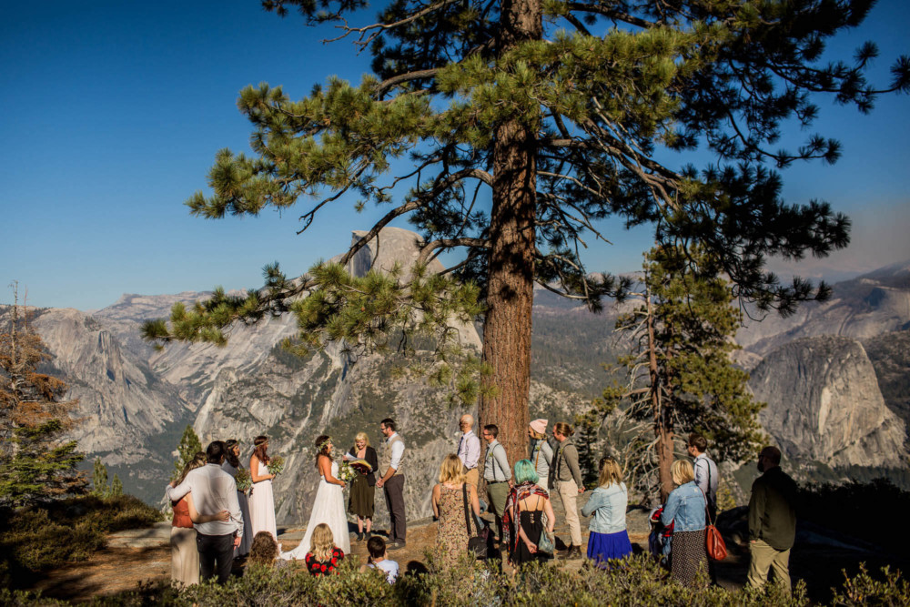 Guests gather around the bride and groom during a wedding ceremony at Glacier Point
