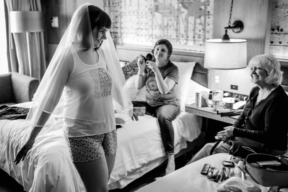 Bride shows off her veil to her mom and a bridesmaid