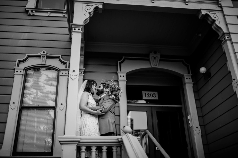 Portrait of a bride and groom on the porch of a Victorian home in Oakland, CA