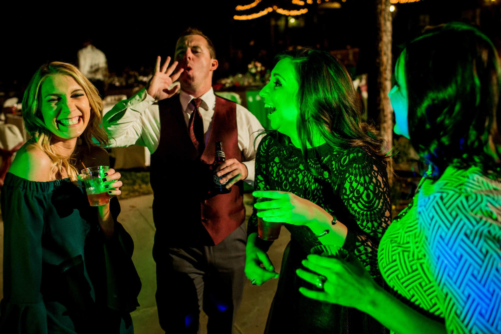 Guests dancing in the colorful DJ lights during the wedding reception