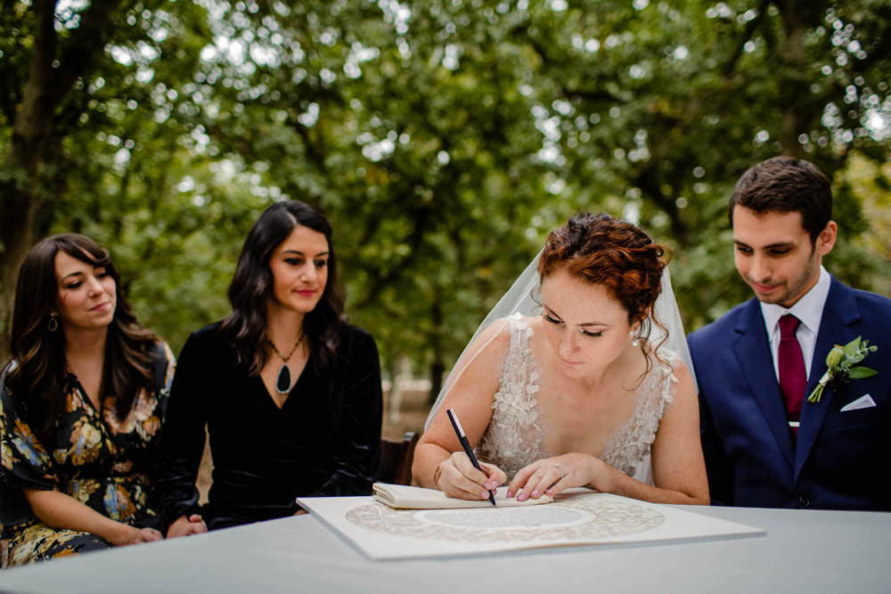 Bride signing the Ketubah in an orchard
