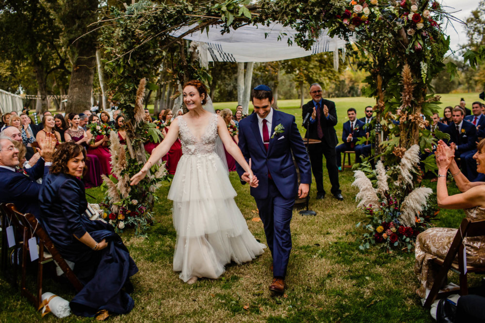 Jubilant bride and groom walk down the aisle after their wedding ceremony