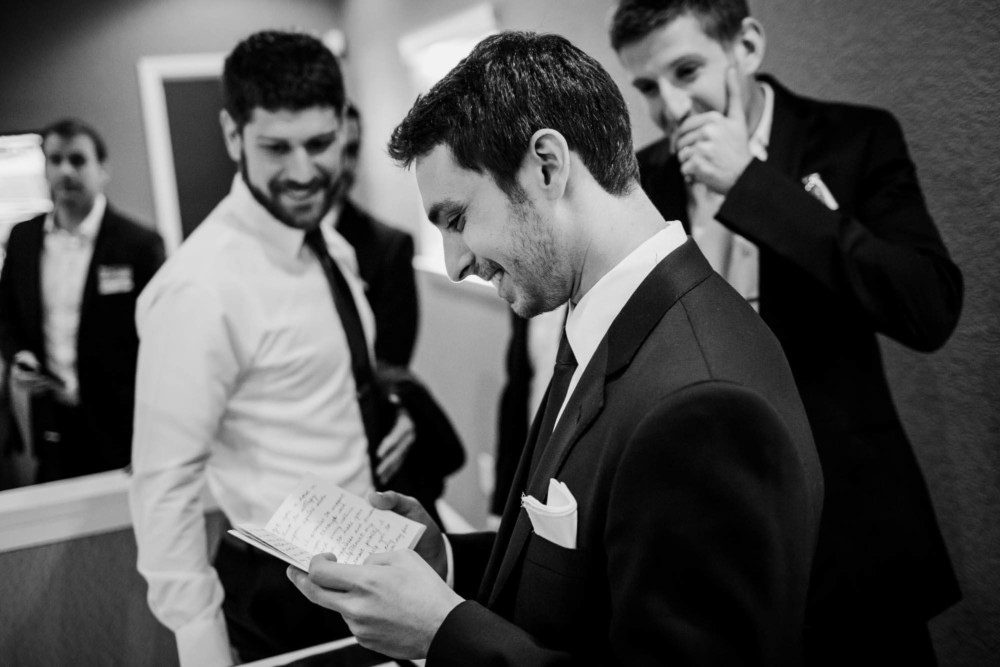 Groom laughs while reading a card from the bride